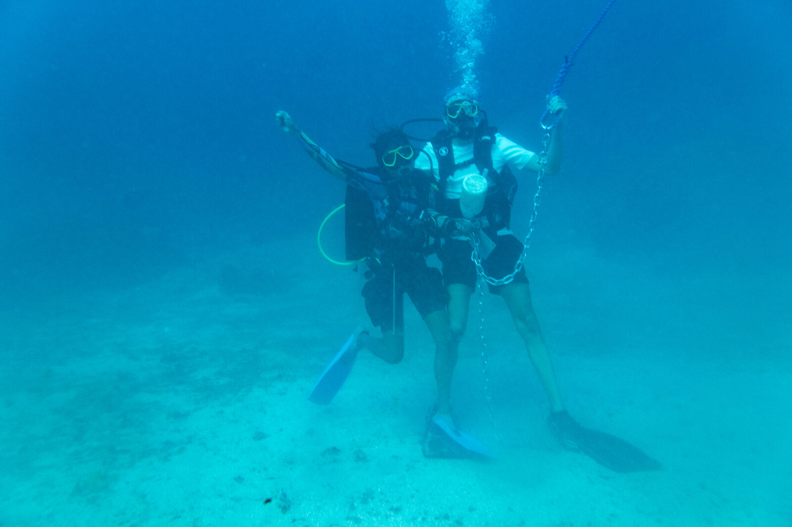 Two divers celebrating underwater next to a new mooring line